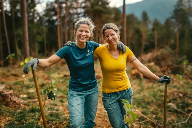 Zwei junge Frauen Arm in Arm beim Aufforsten im Wald